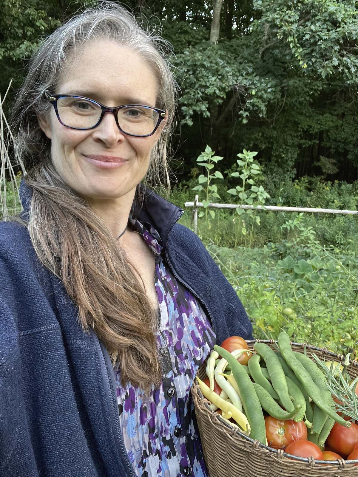 Alida Farrell dans son jardin, un panier de tomates et de haricots dans les bras