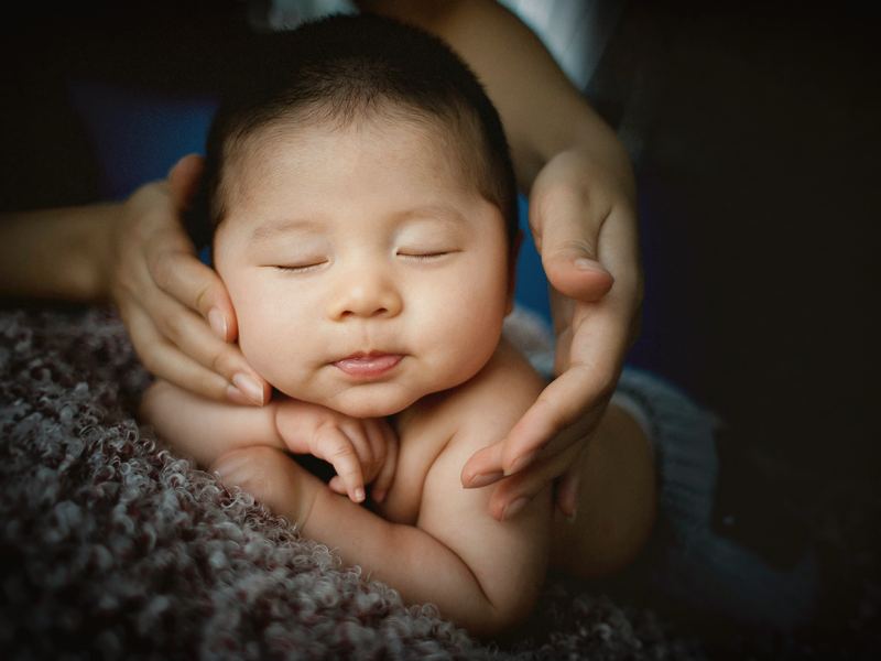 A sleeping newborn, held in an adult's hands