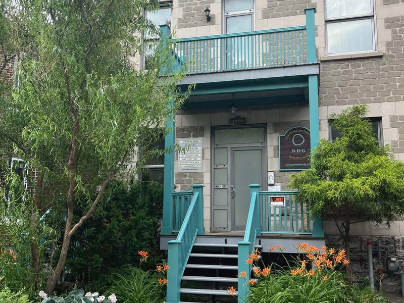 The front of the NDG Health Clinic, grey stone and turquoise stairs in the greenery