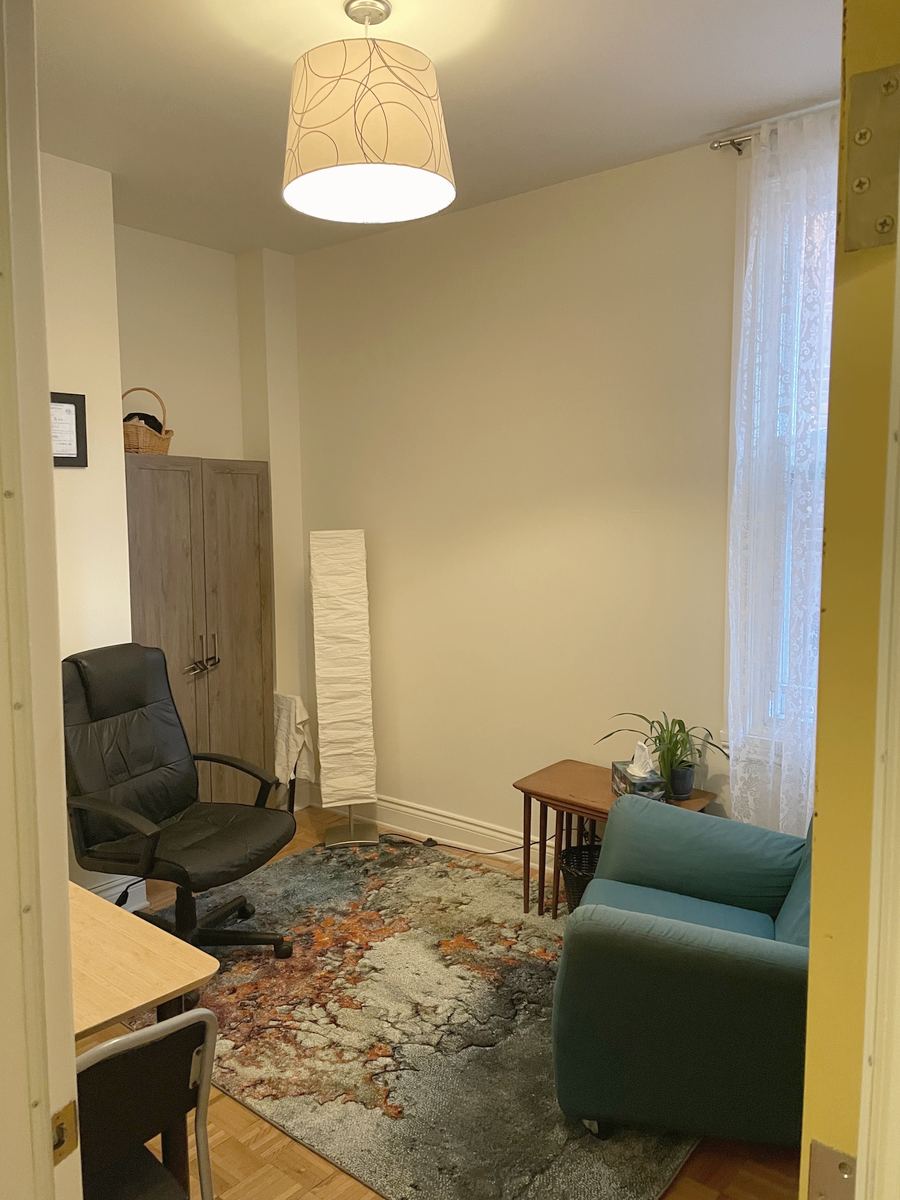 Un bureau aménagé pour les rencontres, un fauteuil bleu canard, une lampe et un tapis