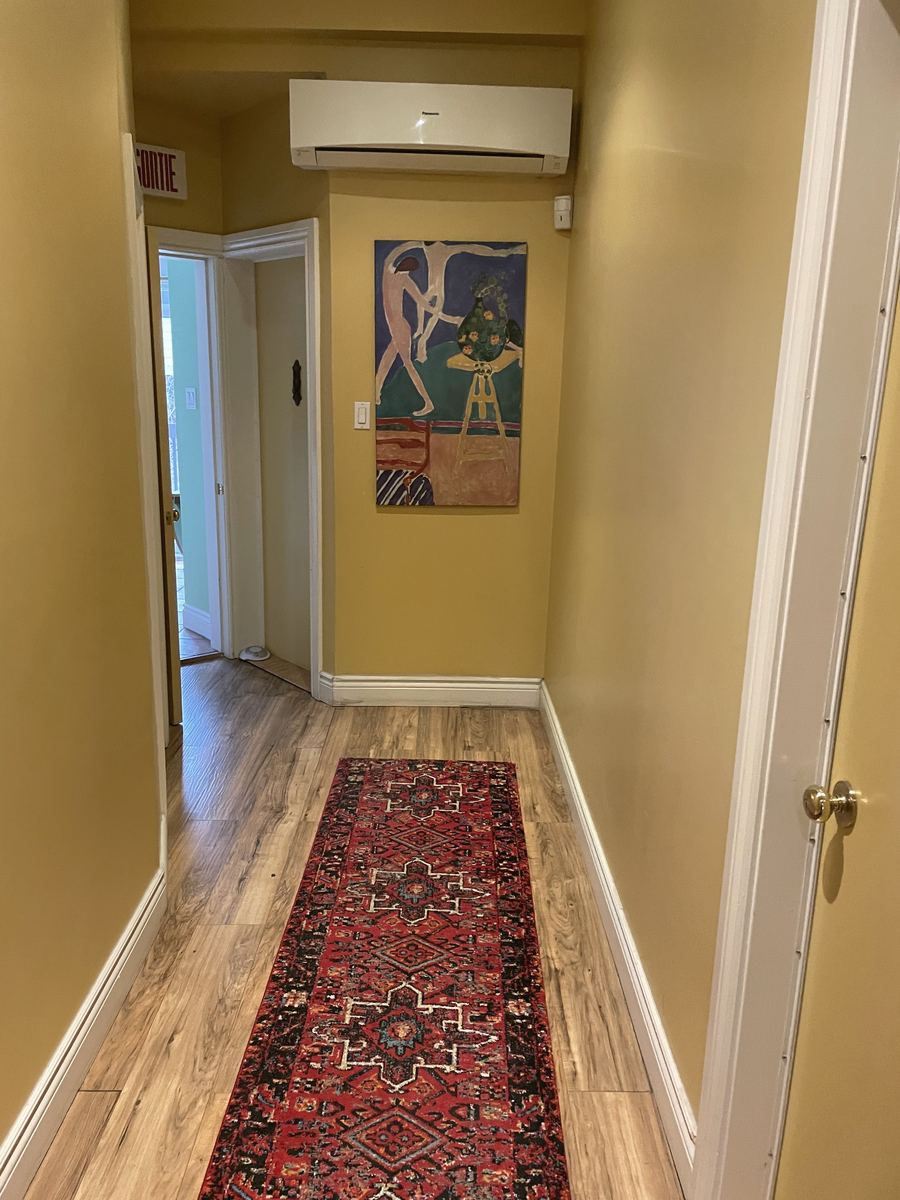 Le corridor de la clinique, murs jaunes, un tapis rouge et une affiche au mur