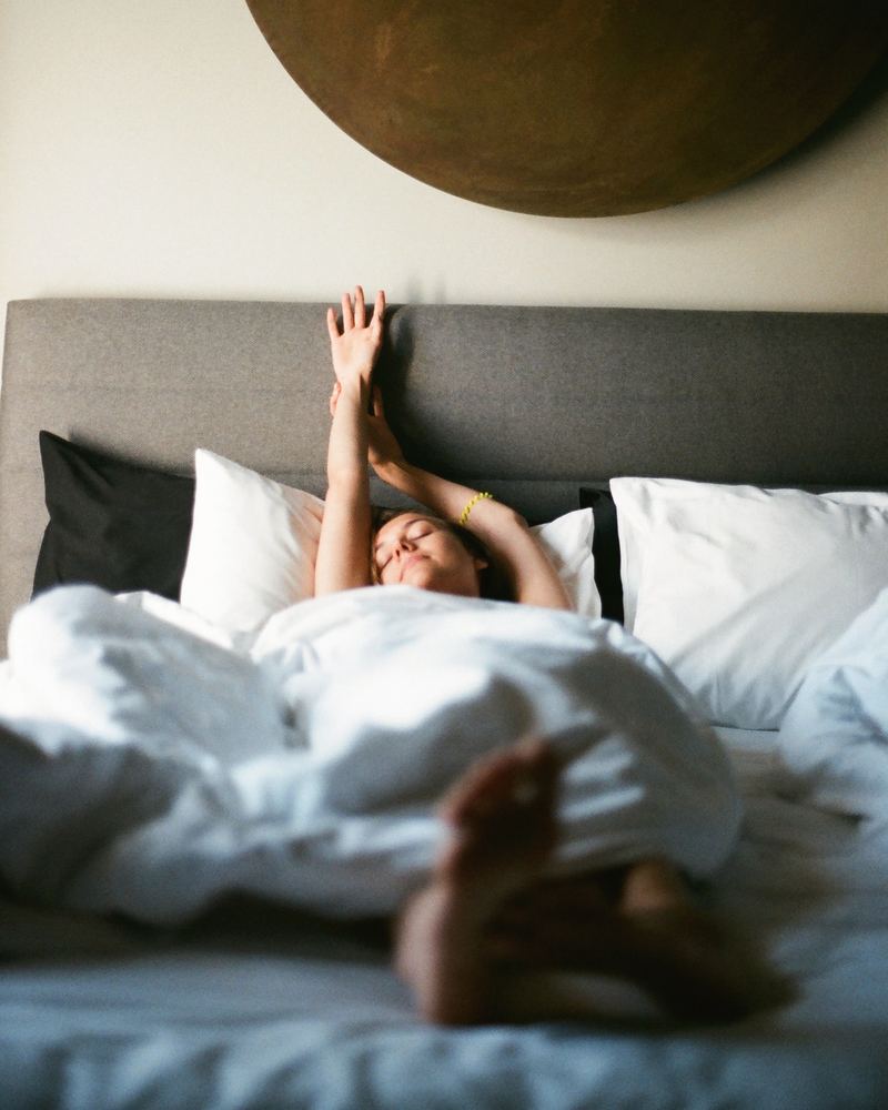 Une femme qui s'étire au réveil dans son lit, image d'ambiance