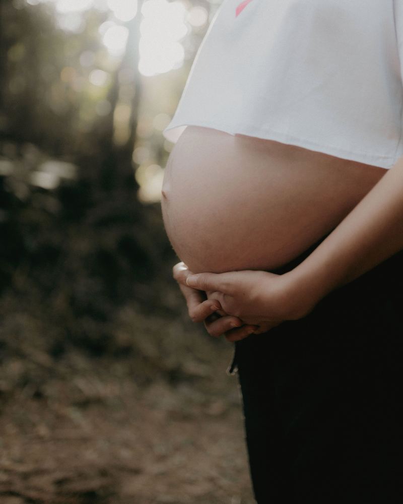 Une femme enceinte qui tient son ventre, dehors, image d'ambiance
